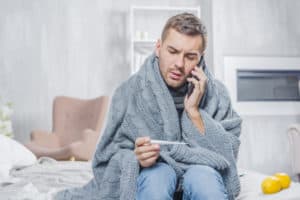 marketing is an ever changing industry, no matter what it’s meant for, young man sitting bed wrapped scarf looking thermometer talking mobile phone